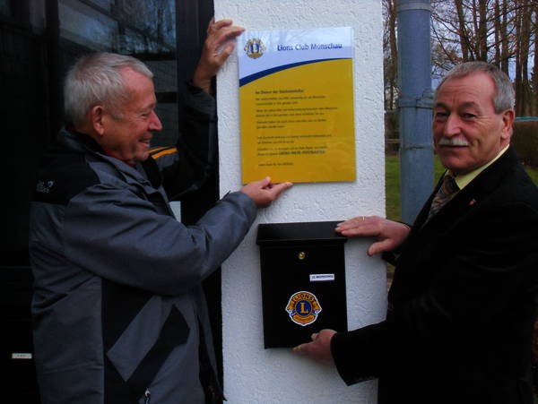 Das Bild zeigt den Vorsitzenden des Lions-Hilfswerk, Hans-Peter Drews, links im Bild, mit dem Bürgermeister der Gemeinde Roetgen, Herrn Manfred Eis, bei der Anbringung des Briefkasten.